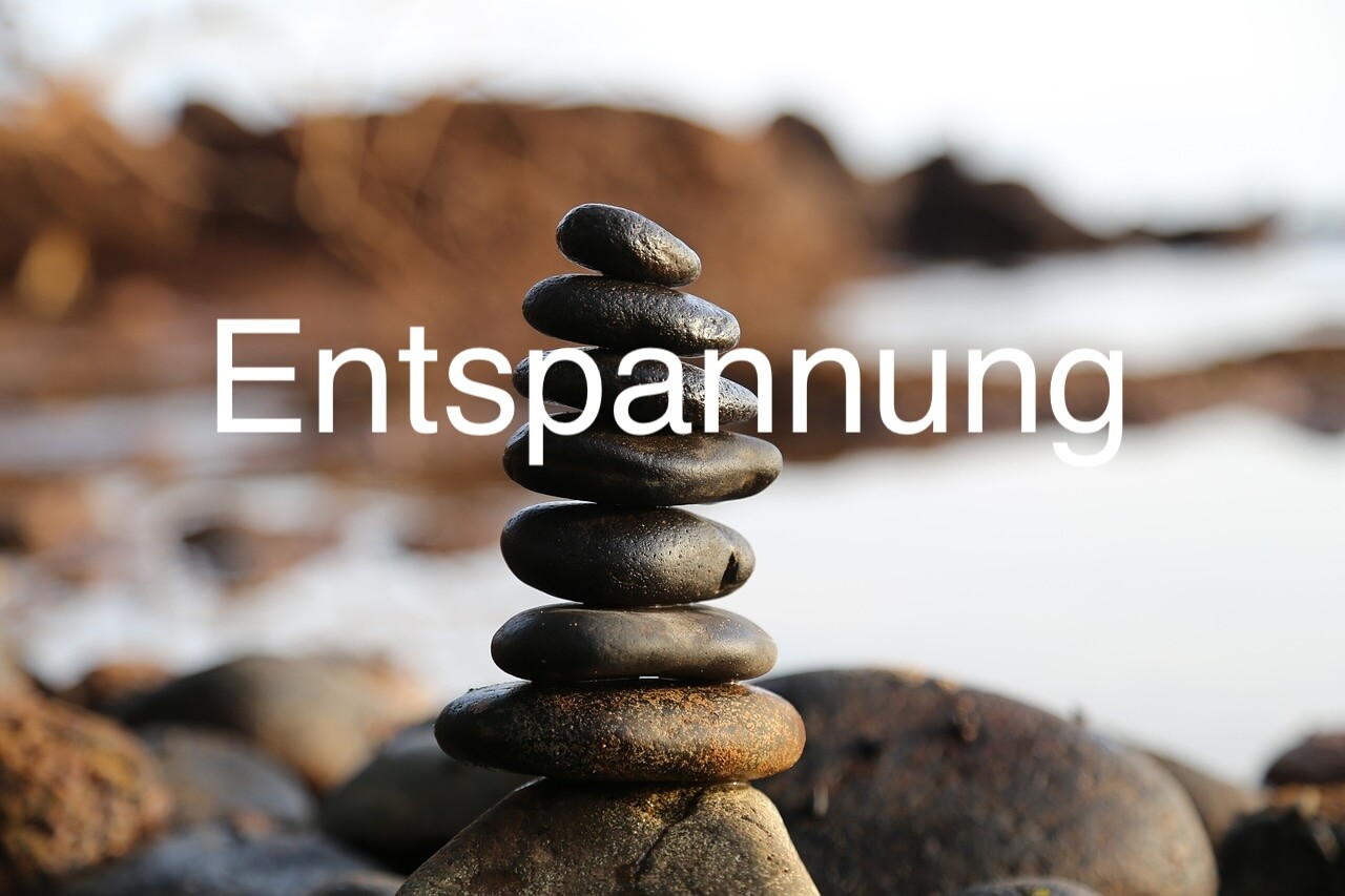 Ein Turm aus Steinen am Meer mit Text Entspannung